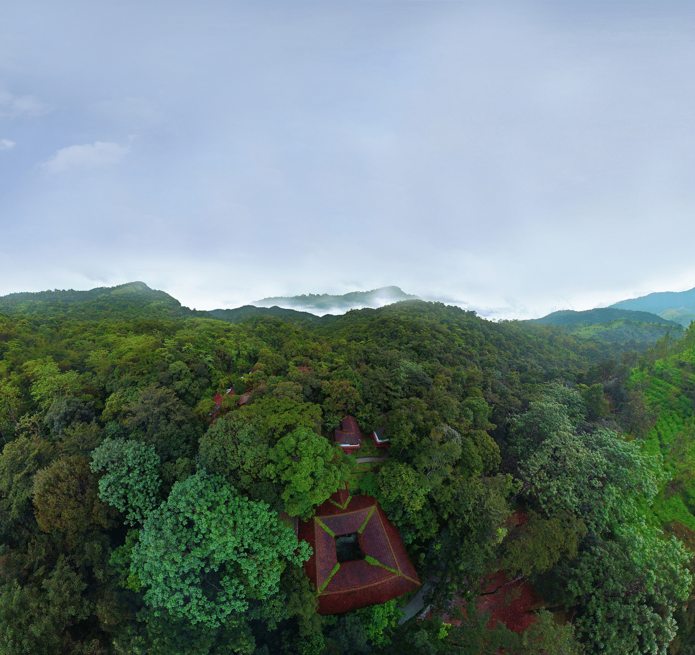 An aerial view of greenery with a backdrop of clear sky | Vythiri Resort, Wayanad